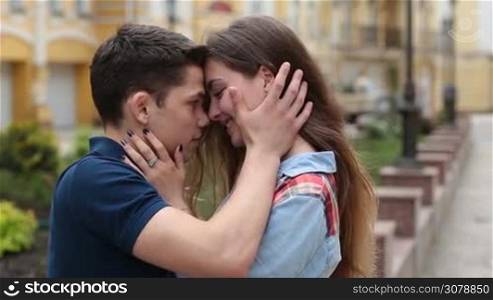 Attractive young couple in love looking at each other and smiling outdoors. Side view. Affectionate couple embracing on city street during romantic date.