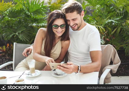 Attractive, young couple in the cafe, uisng smartphone