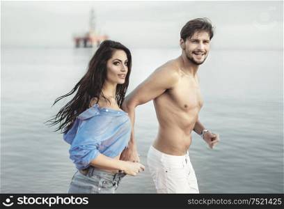 Attractive, young couple running along the seaside