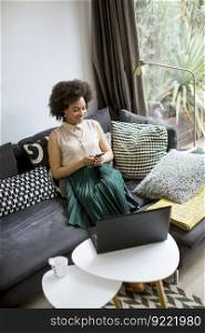 Attractive young curly hair woman working on laptop and using mobile phone at home