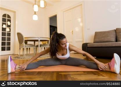 Attractive young female doing stretching exercise in her living room
