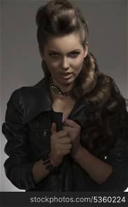 attractive young female posing with fashion dark look, black leather jacket and rock accessories with aggressive expression