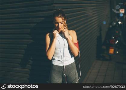 Attractive young female runner taking break after jogging outdoors