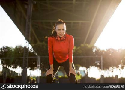 Attractive young female runner taking break after jogging outdoors