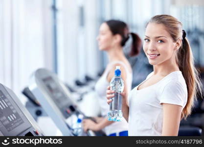 Attractive young girl on a treadmill in fitness club