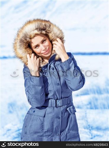 Attractive young lady outdoors in wintertime, wearing stylish winter clothes, warm coat with furry hood, fashionable winter look concept