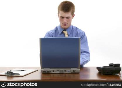 Attractive young man at desk with laptop. Blue button shirt and yellow tie.