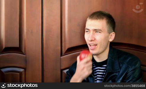 Attractive young man eating apple.