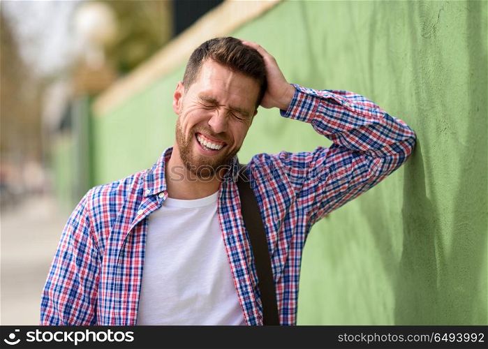Attractive young man laughing outdoors. Lifestyle concept.. Attractive young man laughing outdoors. Funny guy wearing casual clothes in urban background. Lifestyle concept.