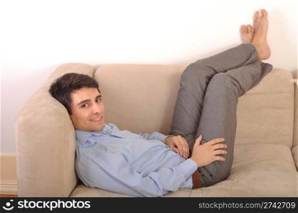 attractive young man lying and relaxing on the couch (isolated on white background)