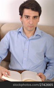 attractive young man reading a business book on the couch