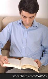 attractive young man reading a business book on the couch