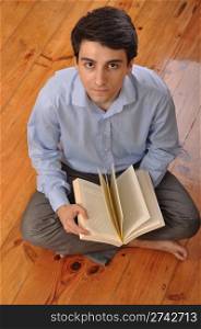 attractive young man reading a business book while sitting on the floor at home