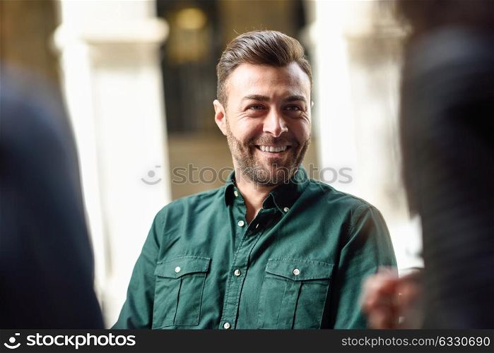 Attractive young man sitting at cafe, talking with friends. Lifestyle and friendship concepts with real people models