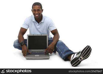 Attractive young man sitting on floor with laptop computer.