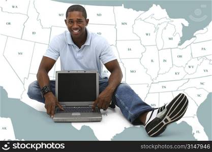 Attractive young man sitting on floor with laptop computer over map of US States.