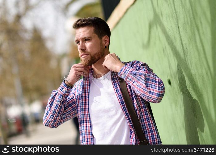 Attractive young man standing in urban background. Lifestyle con. Attractive young man standing in urban background. Guy wearing casual clothes. Lifestyle concept.