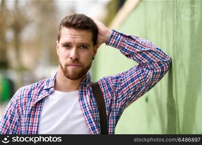 Attractive young man standing in urban background. Lifestyle con. Attractive young man standing in urban background. Guy looking at camera wearing casual clothes. Lifestyle concept.