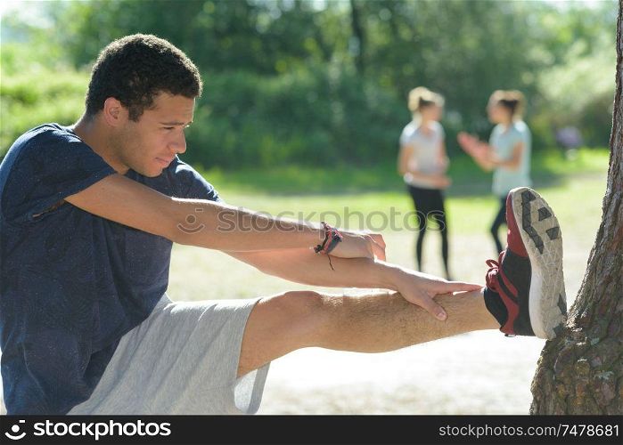 attractive young man stretching in the park before running