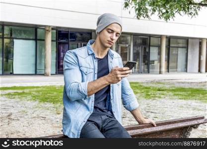 Attractive young man using phone in a public park