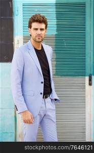 Attractive young man wearing suit standing outdoors.. Attractive man wearing suit standing in urban background.
