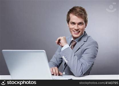 Attractive young man with a laptop on a gray background