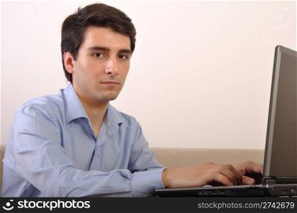 attractive young man with laptop computer sitting on the couch at home