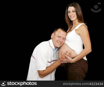 Attractive young married couple expecting a baby. Black background with room for text.