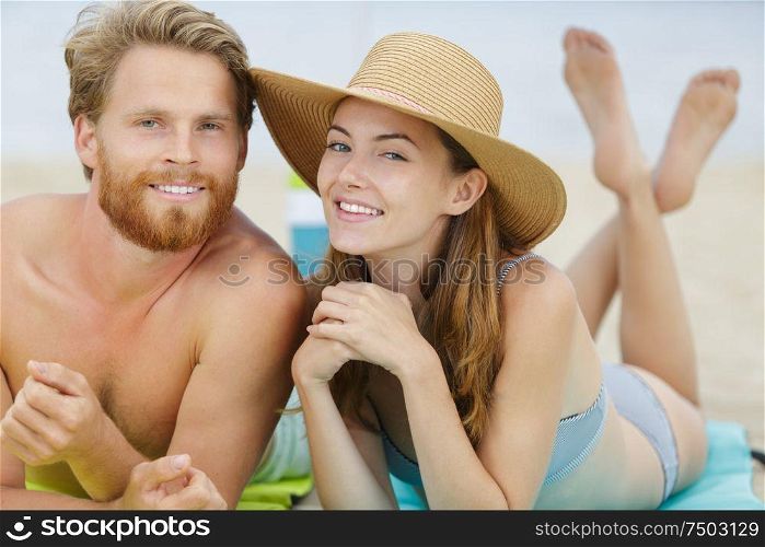 attractive young tourist couple laying down on a white sand