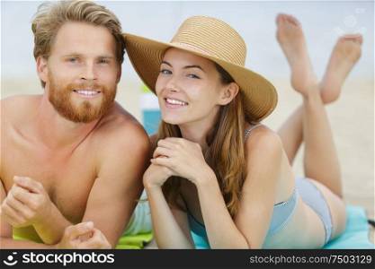 attractive young tourist couple laying down on a white sand