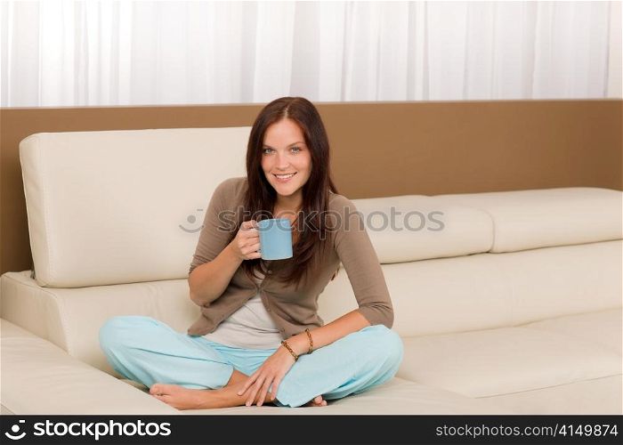 Attractive young woman at modern home sitting sofa drink coffee