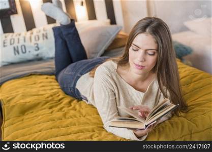 attractive young woman enjoying reading book bed