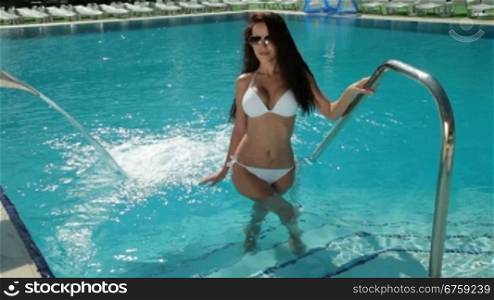 Attractive young woman going out of the pool
