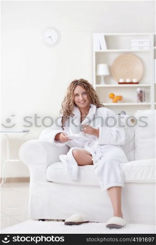 Attractive young woman in a bathrobe with a cup