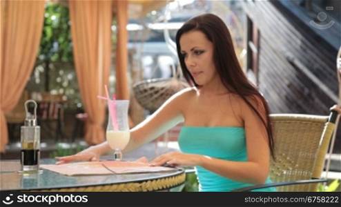 attractive young woman in a cocktail dress having dinner in a restaurant. Waiter setting the table