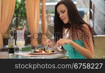 attractive young woman in a cocktail dress having dinner in a restaurant. Greek salad