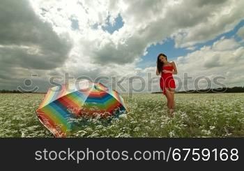 Attractive young woman in a red dress posing in field