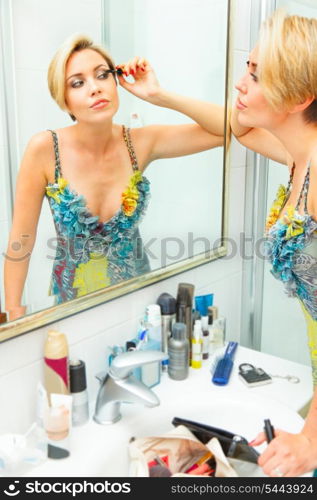 Attractive young woman in bathroom applying mascara&#xA;