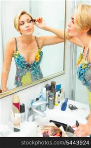 Attractive young woman in bathroom applying mascara&#xA;