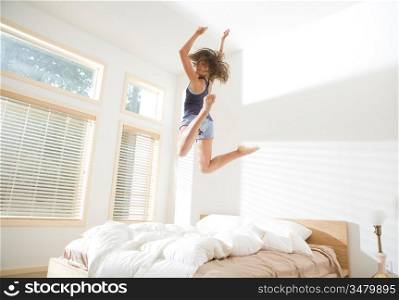 Attractive Young Woman Jumping on Bed and Looking Over Shoulder