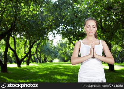 Attractive young woman practices yoga in the park