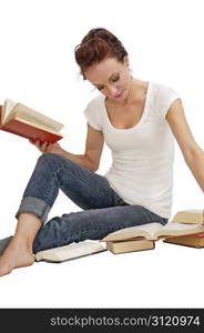 Attractive young woman seated on the floor doing research in old books.