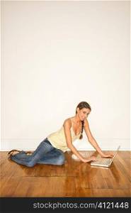 Attractive Young Woman Smiling Sitting on Floor with Laptop