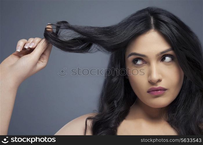 Attractive young woman twisting hair around her finger over colored background
