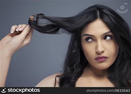 Attractive young woman twisting hair around her finger over colored background