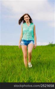 Attractive young woman walking over a green meadow
