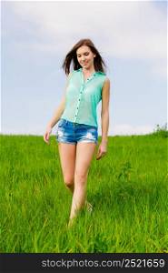 Attractive young woman walking over a green meadow