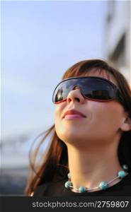 Attractive young woman wearing sunglasses, blue sky background