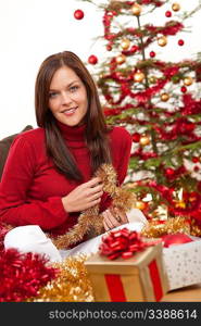 Attractive young woman with Christmas decoration in front of tree