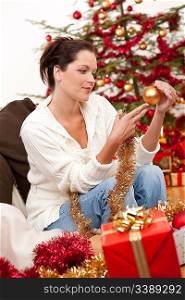 Attractive young woman with Christmas decoration in front of tree